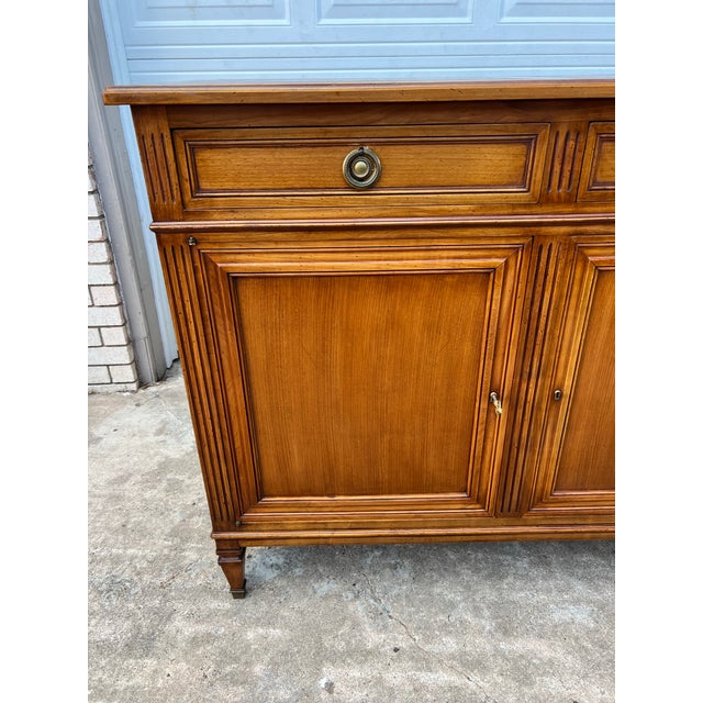 A walnut Louis XVI three-door buffet, French, 19th century, featuring elegant neoclassical lines, paneled doors, and...