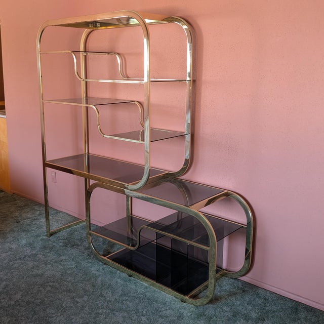 Stunning vintage brass and smoked glass etagere, featuring an elegant tubular brass frame and dark smoked glass shelves...