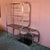 Stunning vintage brass and smoked glass etagere, featuring an elegant tubular brass frame and dark smoked glass shelves...