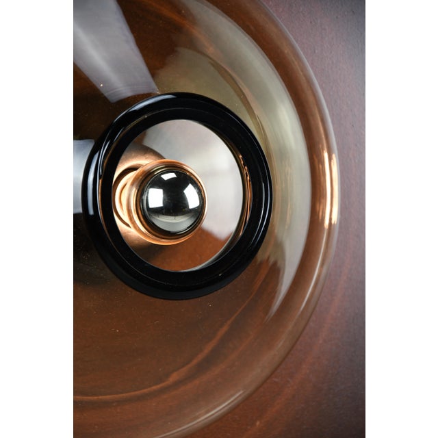 Bot wall lamp — giusto toso for leucos, murano, 1971 a sculptural disc of smoked murano glass, radiating warmth from a...