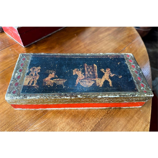 Top depiction of mythological frieze. Wooden box perfect for gloves, jewelry, or trinkets. There's red and gold detailing...
