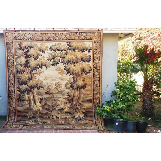 An important Continental antique tapestry panel depicting a beautifully rendered pastoral landscape. The central scene...