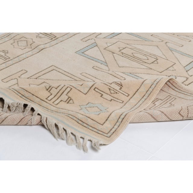 This is a vintage Turkish Oushak rug from the Mid 20th Century. The piece was hand-knotted.