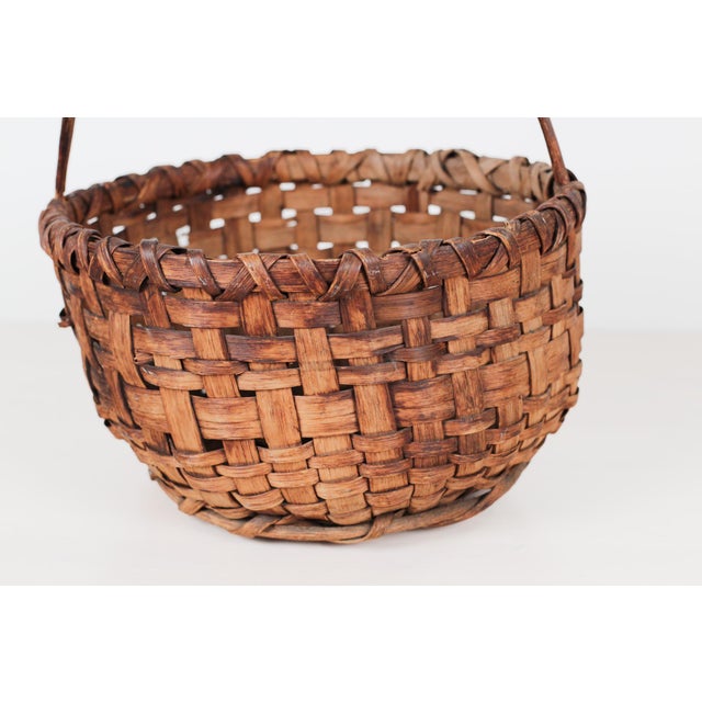 Antique hand-woven American splint basket in the classic gathering form, featuring a steamed and bent hardwood handle...