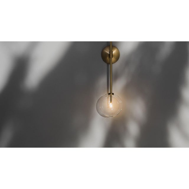 Two glass globes balance on either end of a single vertical arm, poised upon a conical brass mount. This stylish linear...
