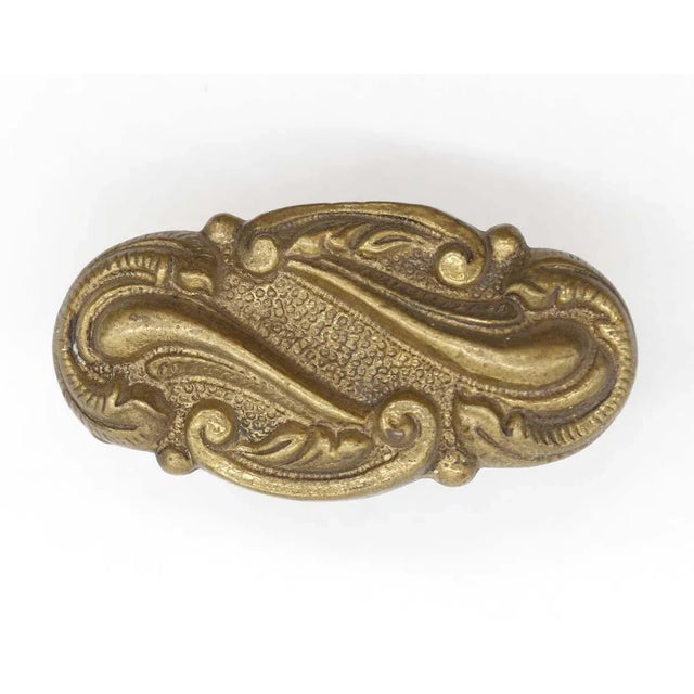 Vintage oval door knob made of brass in an antique finish with curved swirl motifs. Good condition with appropriate wear...