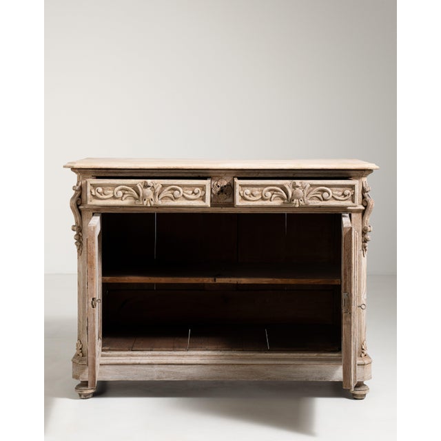 A richly carved Henry II style buffet featuring bold paneling and sculptural relief work inspired by Renaissance design....