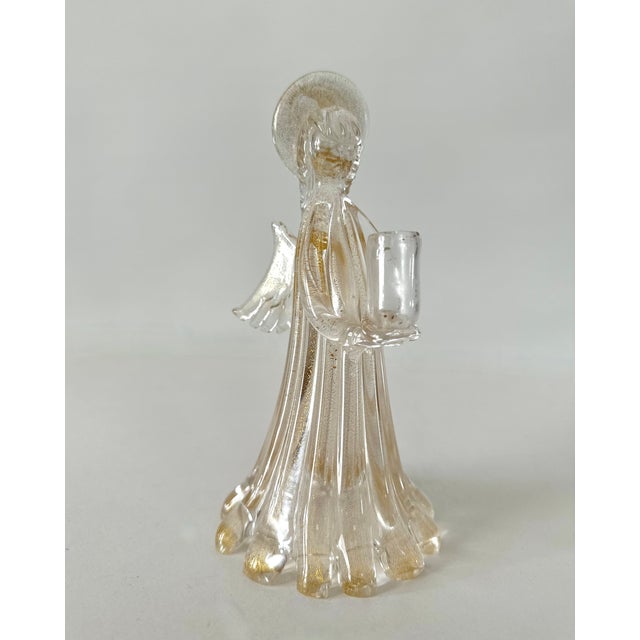 Single Murano glass angel shaped candle holder. Gold foil inclusions to glass give a shimmering effect. 8-1/4" H X 4-1/2"...