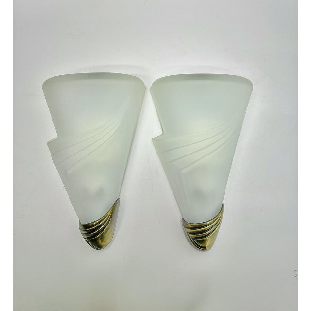 A set of Art Deco style wall lamps made of frosted glass and brass holders. The tapered lamps have an elegant, somewhat...