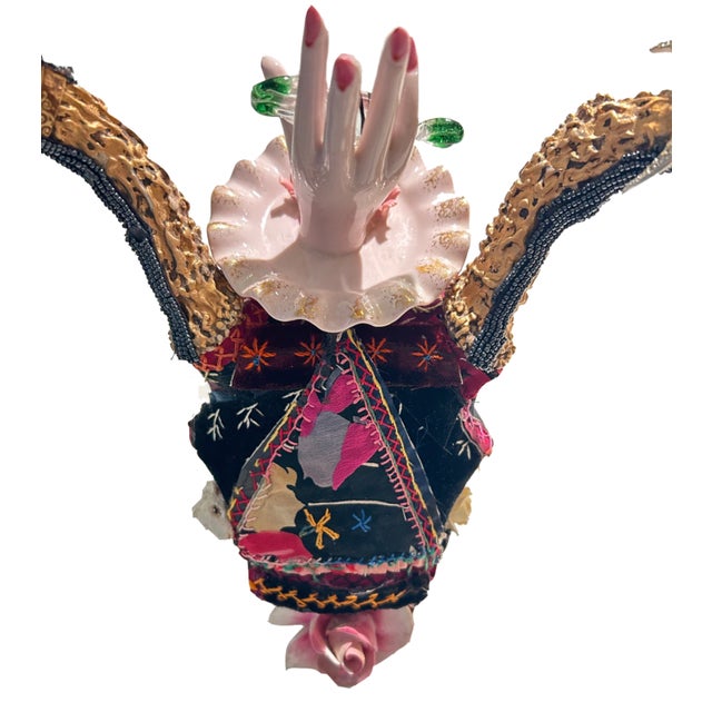 Delightful mixed media skull wall sculpture titled “Giving Sweet”, having a mix of crazy quilt, gold lame bits and pieces,...