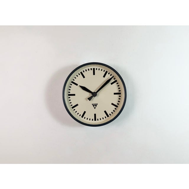 This wall clock was produced by Pragotron in former Czechoslovakia during the 1960s. It features a dark grey metal frame,...