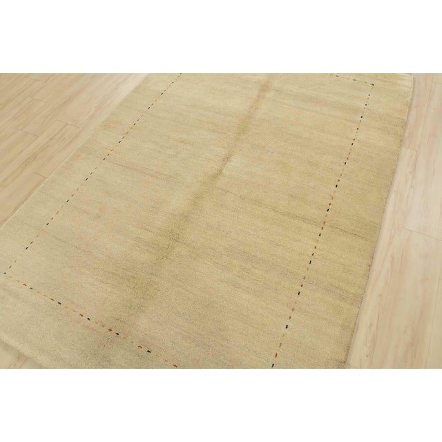 A contemporary Gabbeh rug hand-knotted with an all-wool pile on a cotton foundation. This area rug features a solid beige...