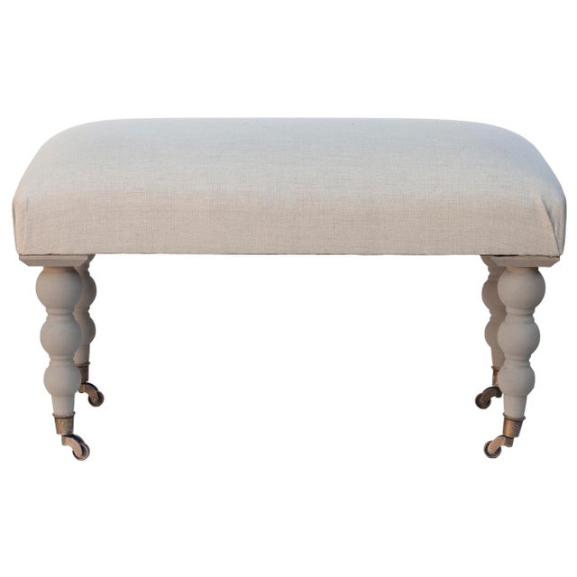 A lovely bench/ottoman upholstered in durable imported Belgian linen with shapely ball-and-ring turned legs. The frame is...