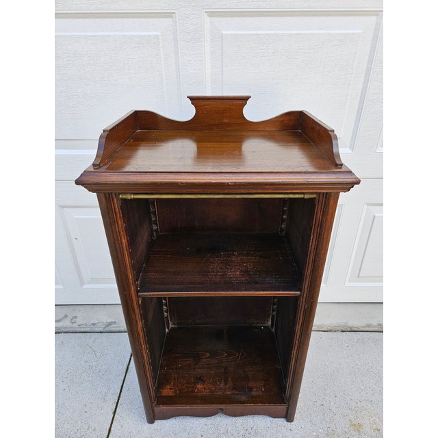 This smaller sized bookcase could double as a bedside table. It has a decorative pediment with an upper lip around the...