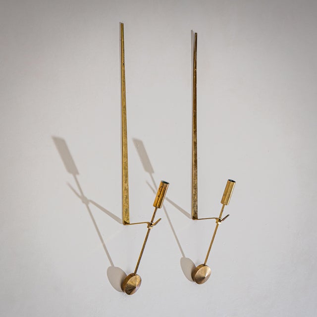 Set of four lancet-shaped wall-mounted candle holders in brass, combining a minimalist yet refined design language....