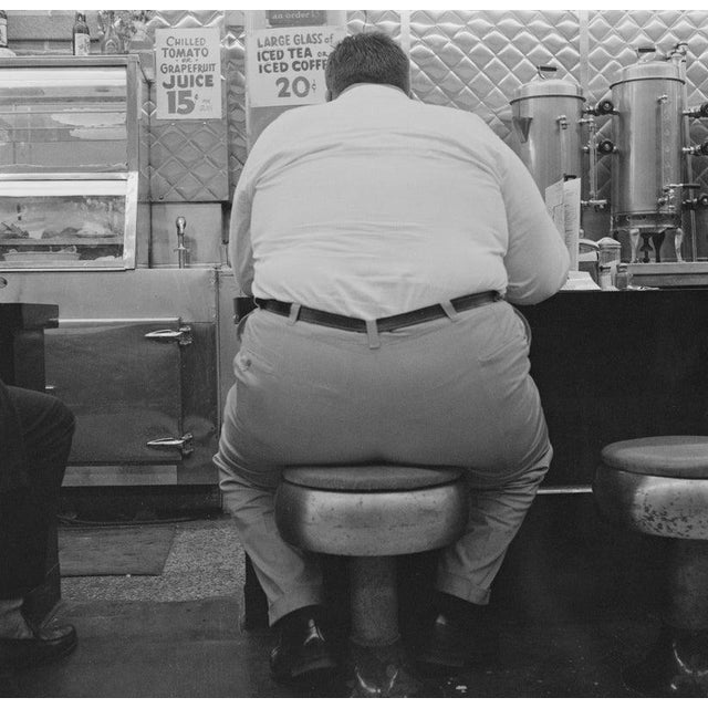 Man In Cafe A large man sitting on a low stool at a cafe in New York, 1964. (Photo by Chris Morphet/Hulton Archive/Getty...