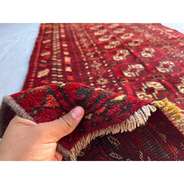 A vintage Afghan Ersari Turkmen rug in the classic Bokhara design — two columns of bold octagonal güls with crisp ivory-...