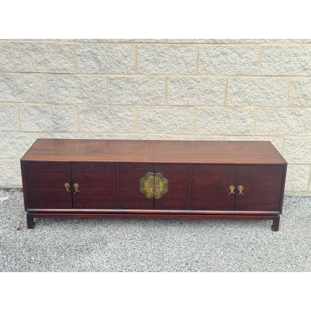 Vintage Chinese elmwood sideboard with a long, low profile and richly toned wood grain. The restrained case is accented by...