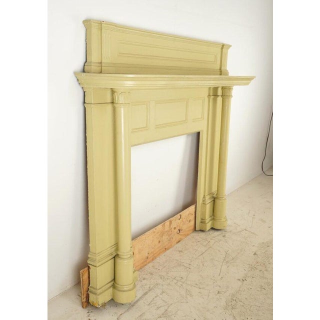 Colonial Revival wood mantle painted in a muted yellow-green hue. The design is influenced by Neoclassical architecture,...