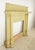 Colonial Revival wood mantle painted in a muted yellow-green hue. The design is influenced by Neoclassical architecture,...