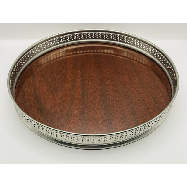 An open-work silver plate serving tray with a center panel made of Formica in a rich mahogany wood tone, perfect for...