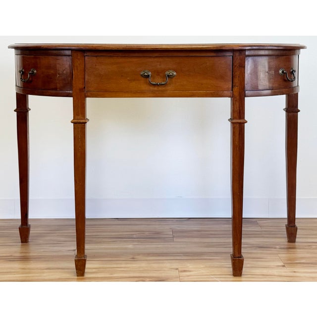 Vintage traditional wood demi-lune console table featuring four tapered Hepplewhite style legs. legs and brass hardware....