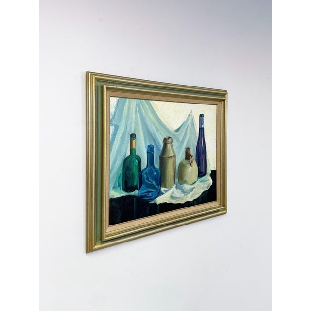 This vintage original oil painting presents a classic still life composition, featuring five bottles and jugs of varying...