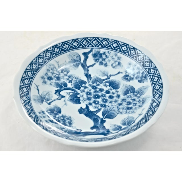 Japanese blue and white ceramic eight inch bowl with a cherry blossom scene encircled by an intricate blue band on the...
