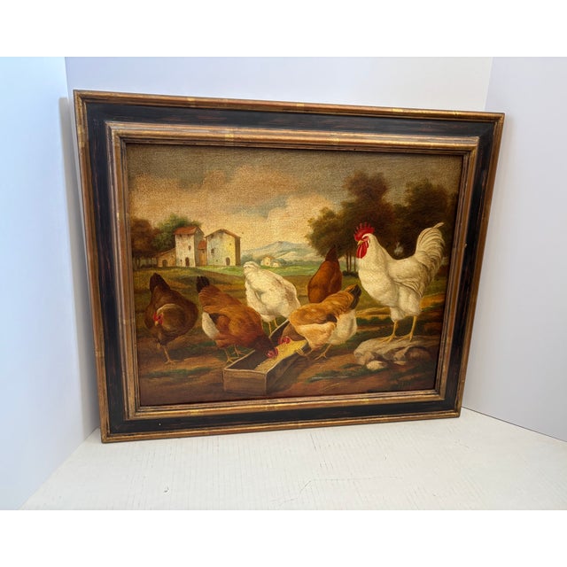 This framed oil painting depicts a flock of chickens and rooster gathered around a wooden feeding trough in a rustic,...
