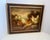 This framed oil painting depicts a flock of chickens and rooster gathered around a wooden feeding trough in a rustic,...