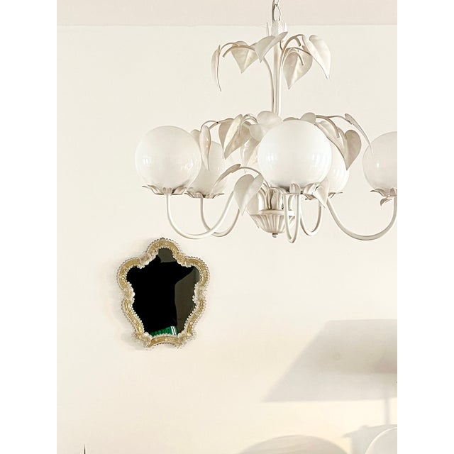 Authentic 1970s Murano wall mirror featuring elegant hand-crafted floral glass decorations mounted on a wooden base. The...