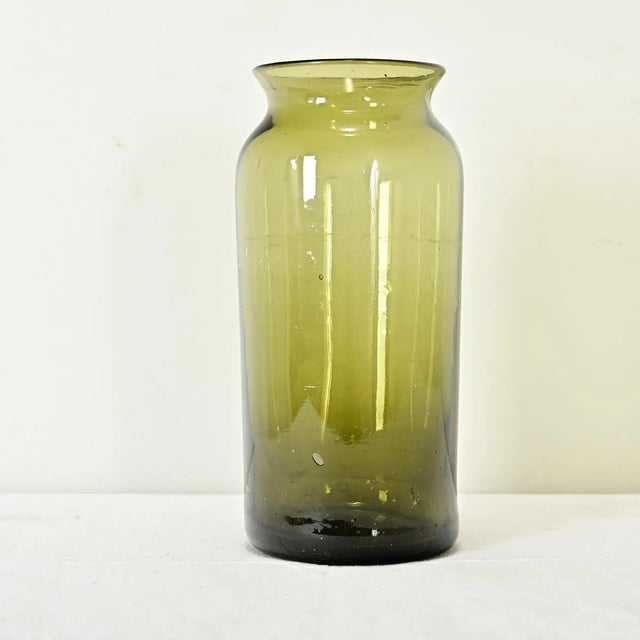 Dimensions: 10 ¾” H x 4 ½” W x 4 ½” D French 18th century olive-green glass pickling jar or kitchen storage jar. The...