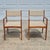 This is a pair of Danish modern style teak arm chairs by D-Scan. The chairs have solid teak frames with sleek midcentury...