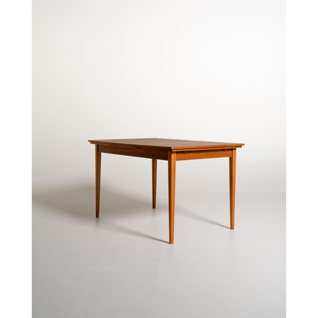 Scandinavian-made dining table in teak and stained beech, with a rectangular top and two 40 cm extendable side extensions....