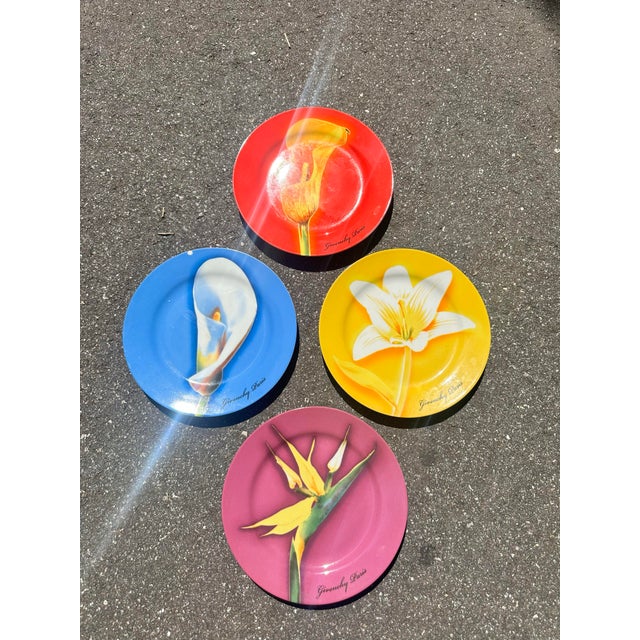 Set of four Givenchy Paris porcelain plates, in red, blue, yellow and purple, each featuring a different flower. Signed on...