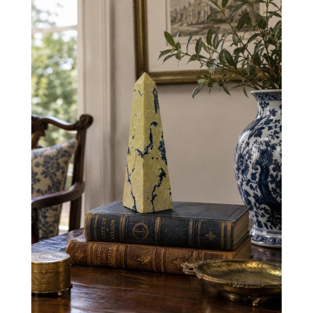 A beautifully proportioned marble obelisk in richly veined shades of yellow, cream, grey, and black. The sculptural...