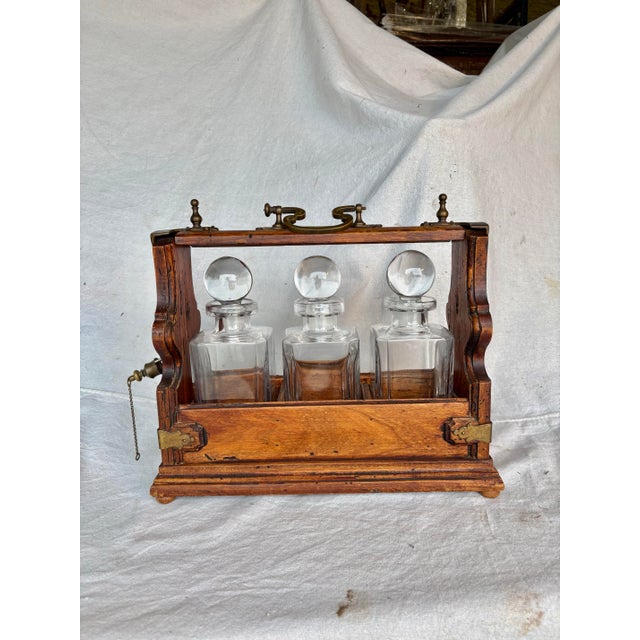 This Early 20th Century English Three Decanter Tantalus was crafted from oak in the early 1900's. The case is composed of...
