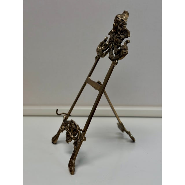 Vintage ornate brass display easels featuring winged motifs of Minerva (the goddess of wisdom) and Poseidon (the god of...