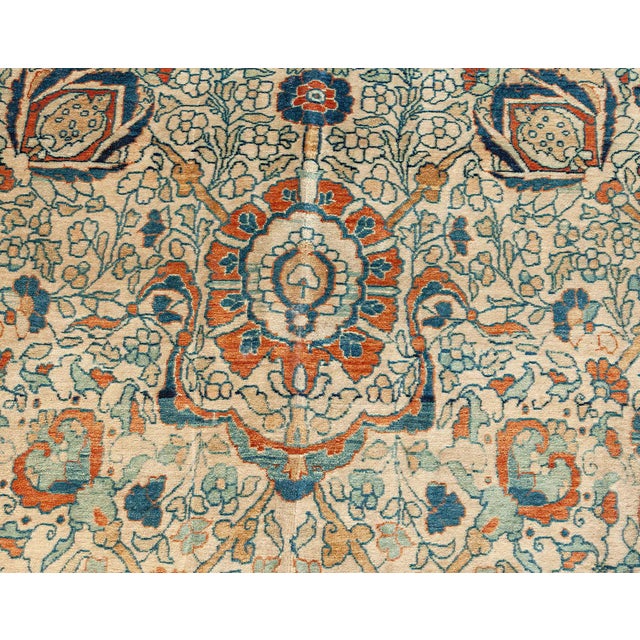 An antique Persian Tabriz carpet, the oatmeal field with an orange-accented palmette, cloud band and floral spray field...