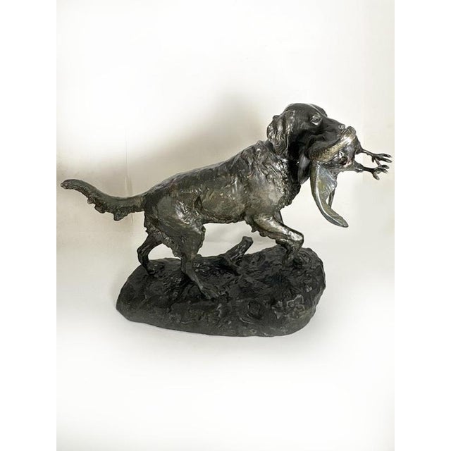 French terracotta sculpture dating from the 19th century, depicting a hunting dog carrying a game bird in its mouth. The...