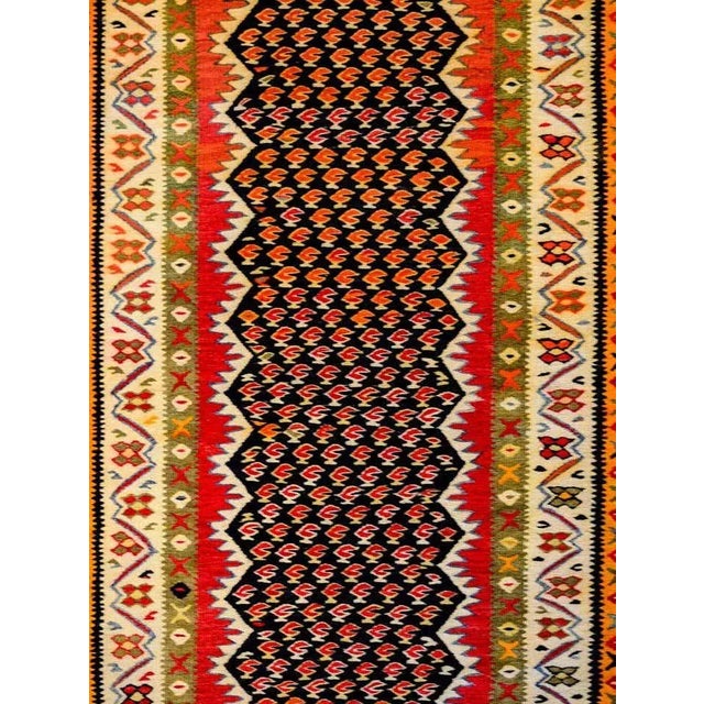 A wonderful mid-20th century Persian Kurdish Kilim runner with an all-over crimson paisley pattern on a black background...