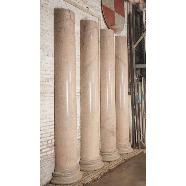 Set of four antique granite Neoclassical columns with rounded bases. They have a light pink hue with the graining typical...