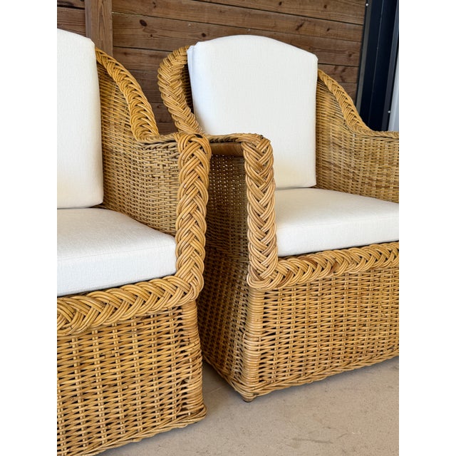 A beautiful pair of vintage woven rattan and wicker lounge armchairs featuring sculptural curved backs, gracefully sloping...