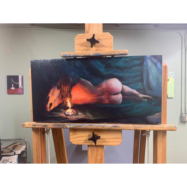This oil painting depicts a reclining figure, draped in soft shadows and illuminated by the warm glow of a candle. The...
