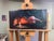 This oil painting depicts a reclining figure, draped in soft shadows and illuminated by the warm glow of a candle. The...