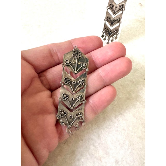 Handcrafted vintage silver filigree dangle earrings featuring articulated geometric chevron tiers and delicate floral...