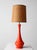 Vintage mid-century ceramic table lamp showcasing a striking sculptural silhouette and a vibrant orange glazed finish. The...