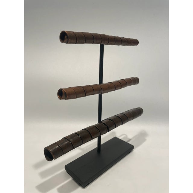 A trio of spiral hair ornaments displayed on a custom mount. From the Arussi people of Ethiopia, these forms were used to...