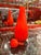 A striking Italian art glass “Circus Bottle” in a vivid orange hue. The sculptural design features an elongated, tapered...