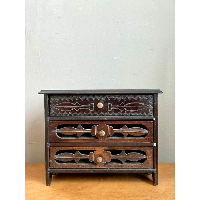 This vintage miniature chest is a charming study in folk-art carving, scaled like a tabletop curio. A slim, overhanging...